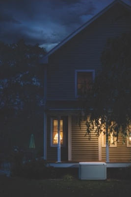 left side of house at nighttime with a propane generator in yard